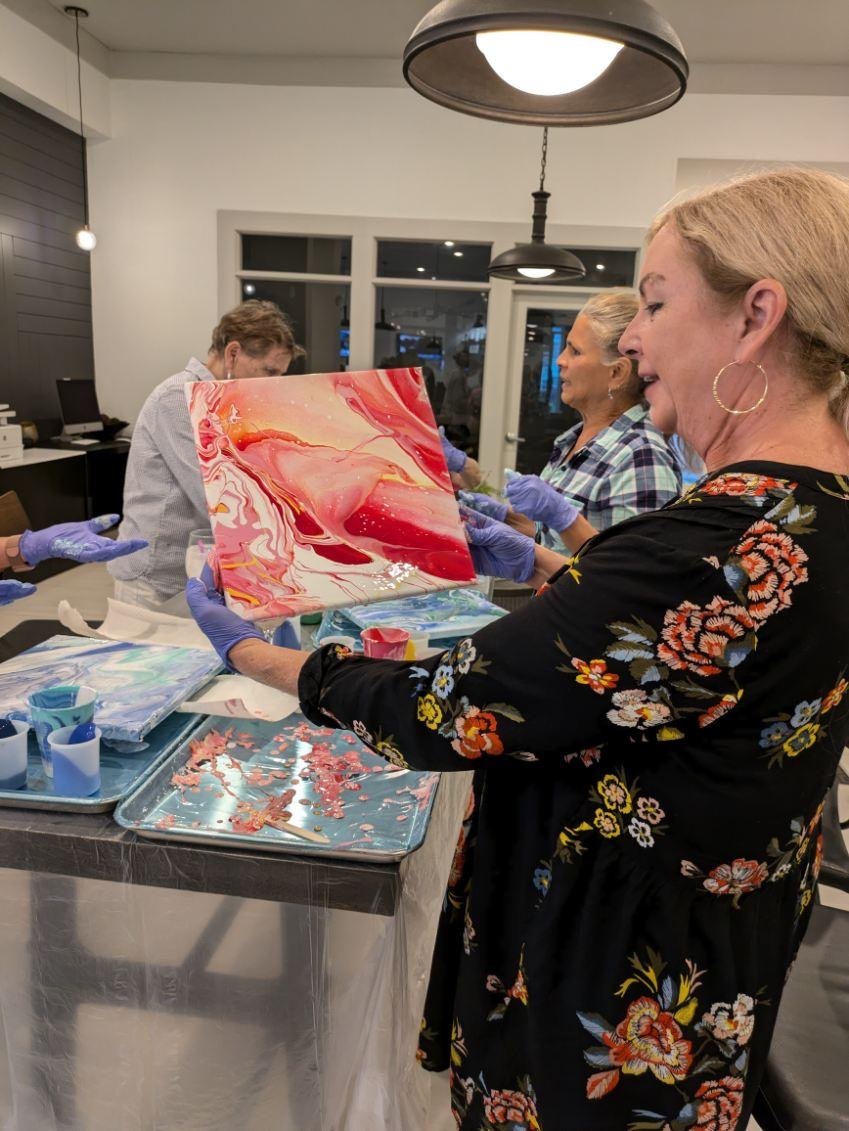 An older adult presenting her finished acrylic pour painting