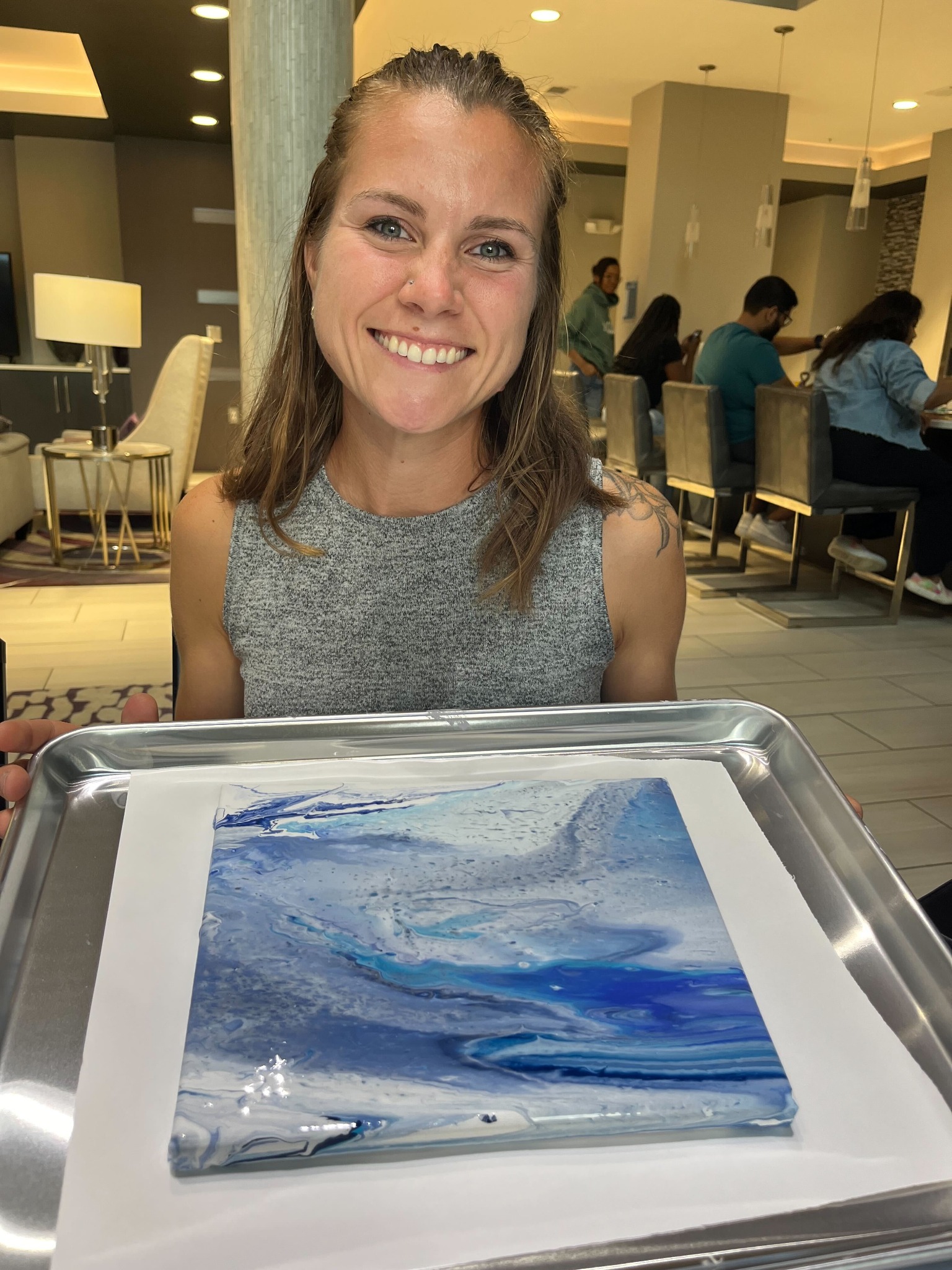 A participant smiling with a freshly poured acrylic canvas