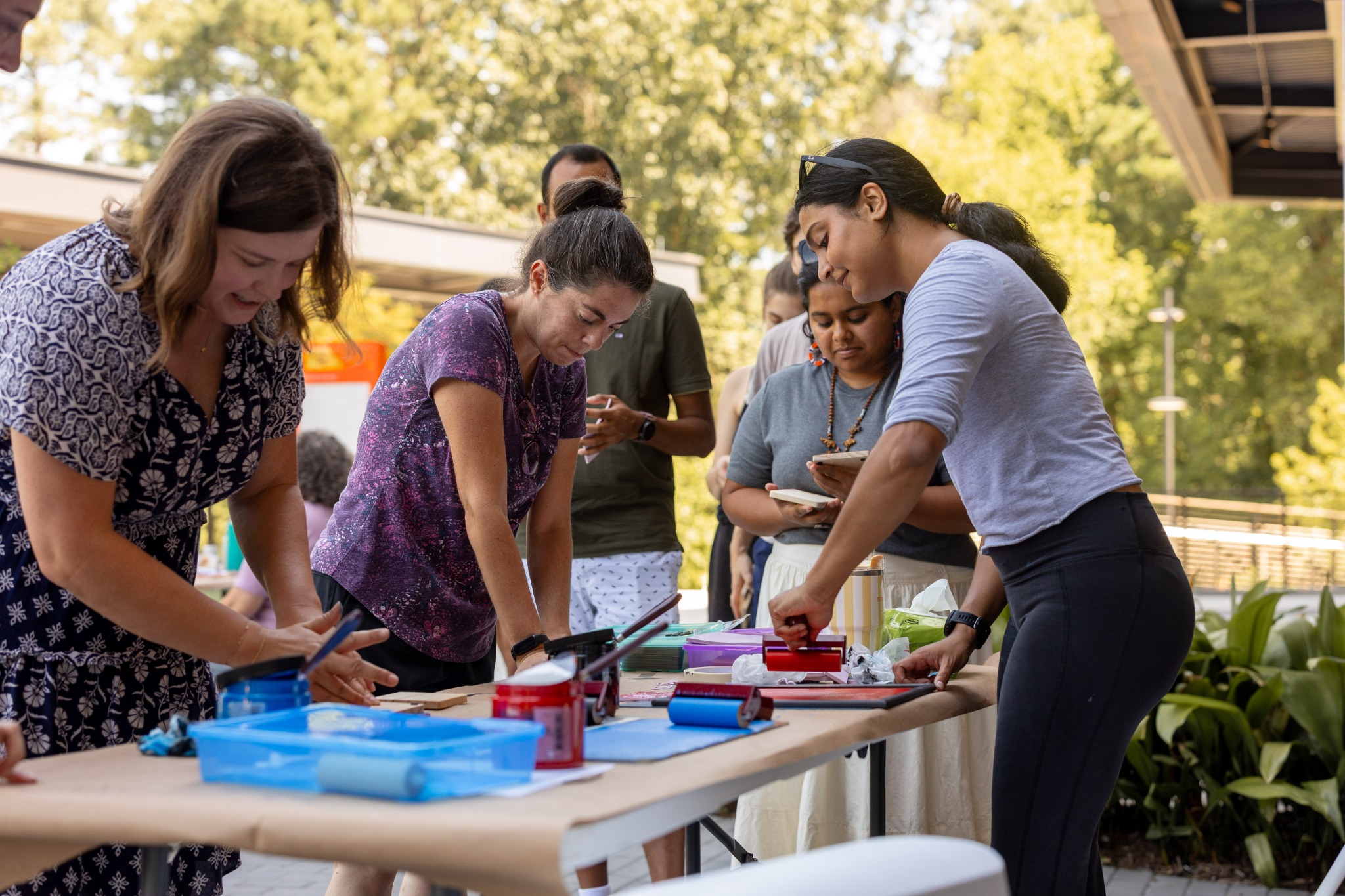 Wide view of an outdoor printmaking event with many tables