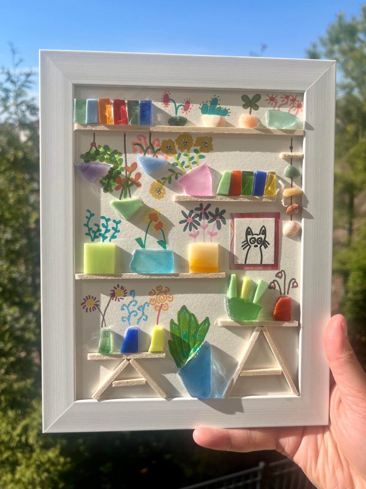 A miniature sea glass bookshelf scene framed as shelf art