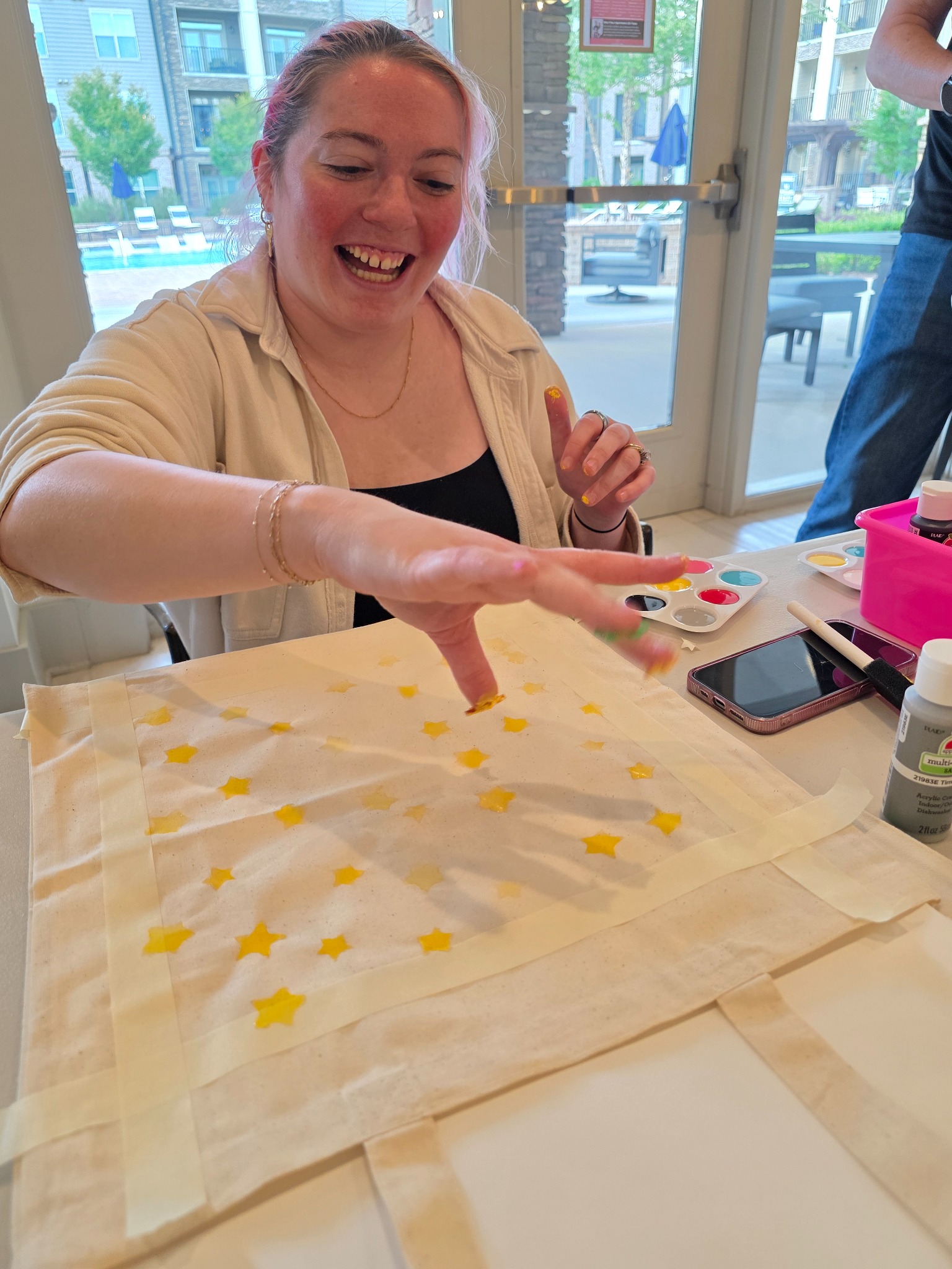 Hands rolling ink and printing a carved block onto a canvas tote
