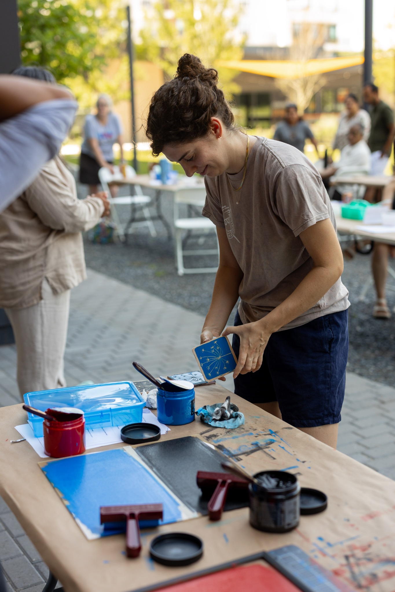 Participants block-printing at long outdoor tables on a sunny afternoon